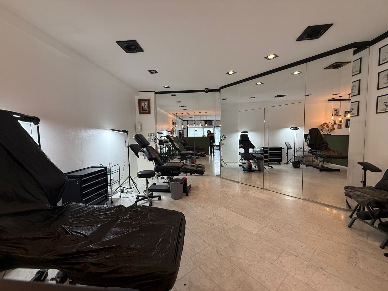 Studio-Innenraum mit Spiegelwand, Tattoo-Liegen und Marmorboden