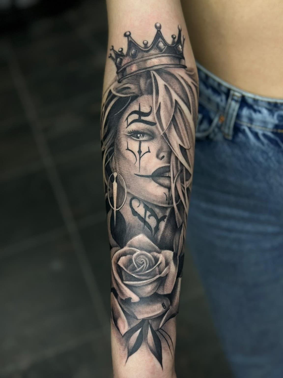Schwarz-Grau-Realismus-Tattoo: Frauenporträt mit Krone und Rose am Unterarm